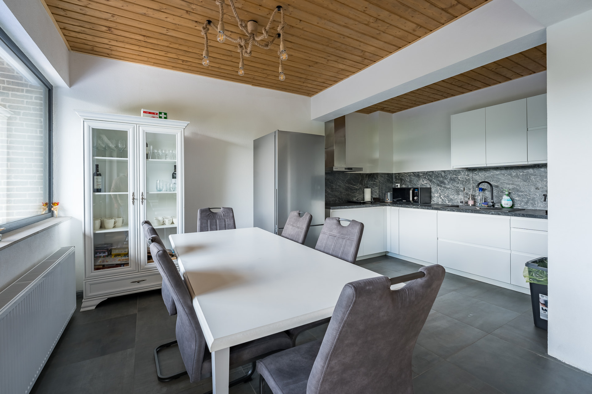 Fully equipped kitchen at Cabanele Carmel, with a long table for group meals and a wooden ceiling