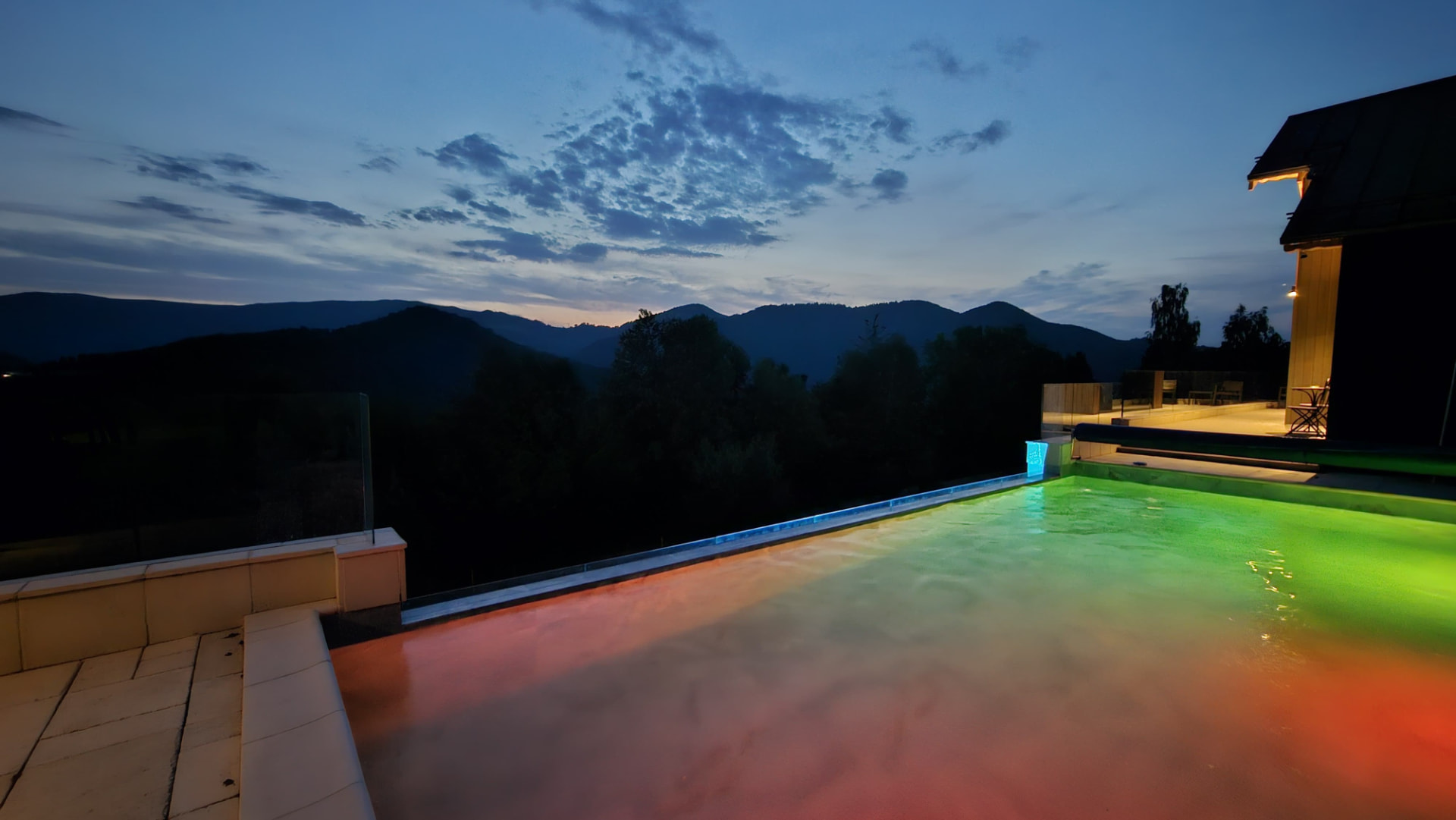 Cabanele Carmel in the mountain landscape of Muntele Rece — the pool lit up in the evening, above the valley