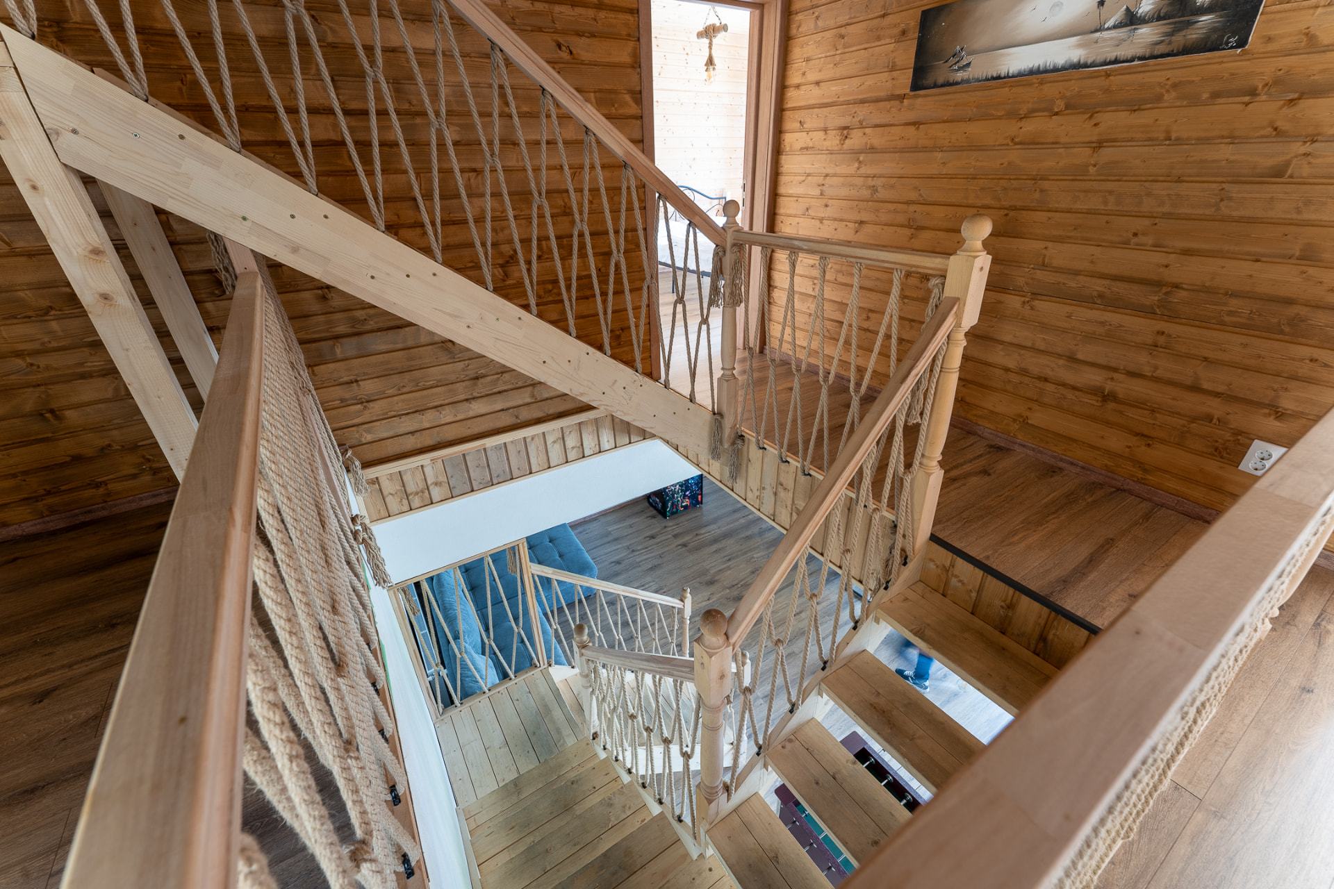 The interior wooden staircase with rope netting, seen from above toward the ground-floor living room