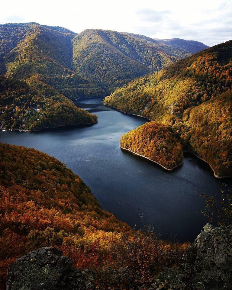 Lacul Tarnița surrounded by the forested slopes of the Gilău Mountains, in autumn colours