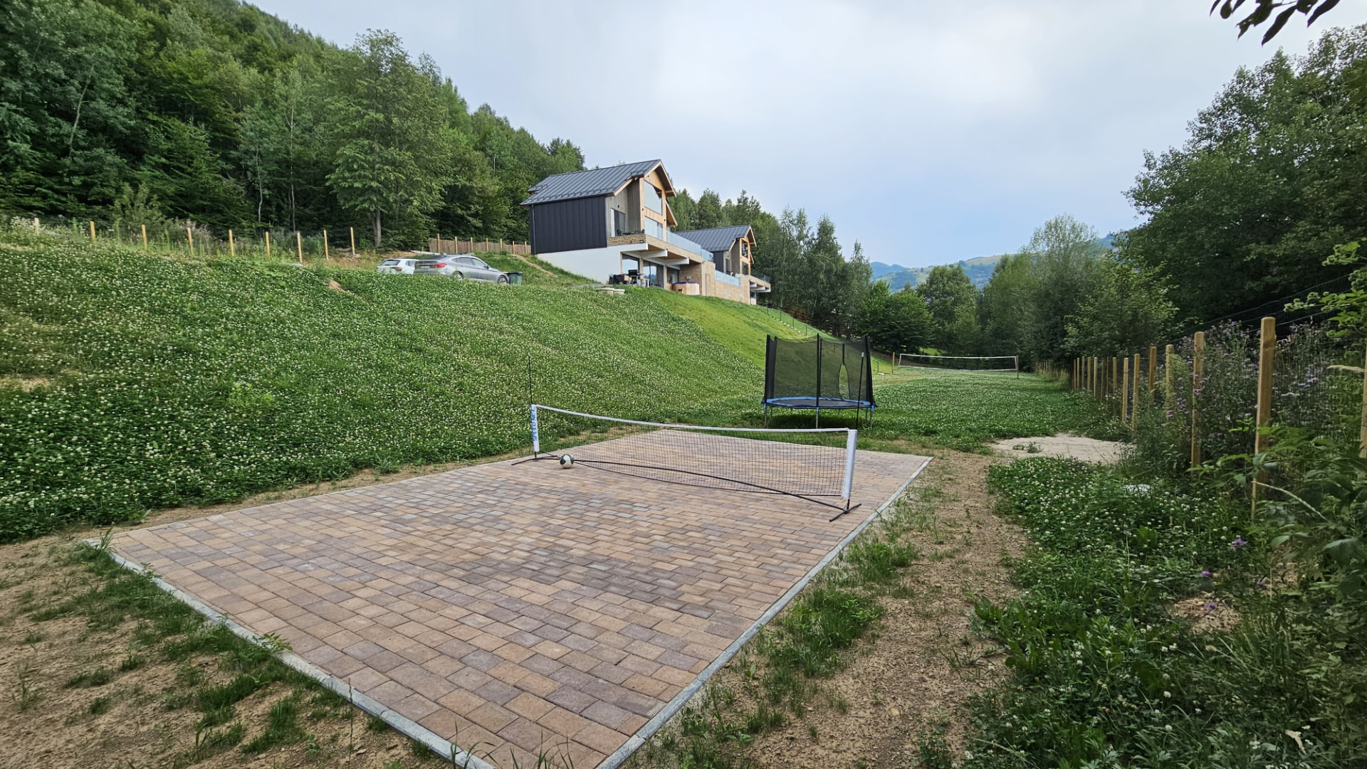 The paved sports court and trampoline on the lawn in front of the cabins
