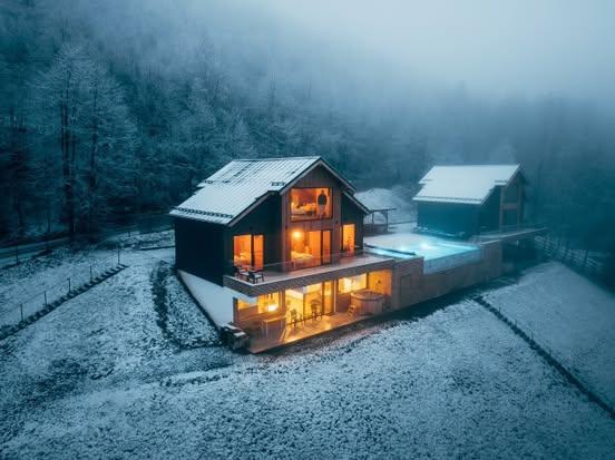 The cabins seen from above on a winter morning, with the forest and meadows blanketed in snow