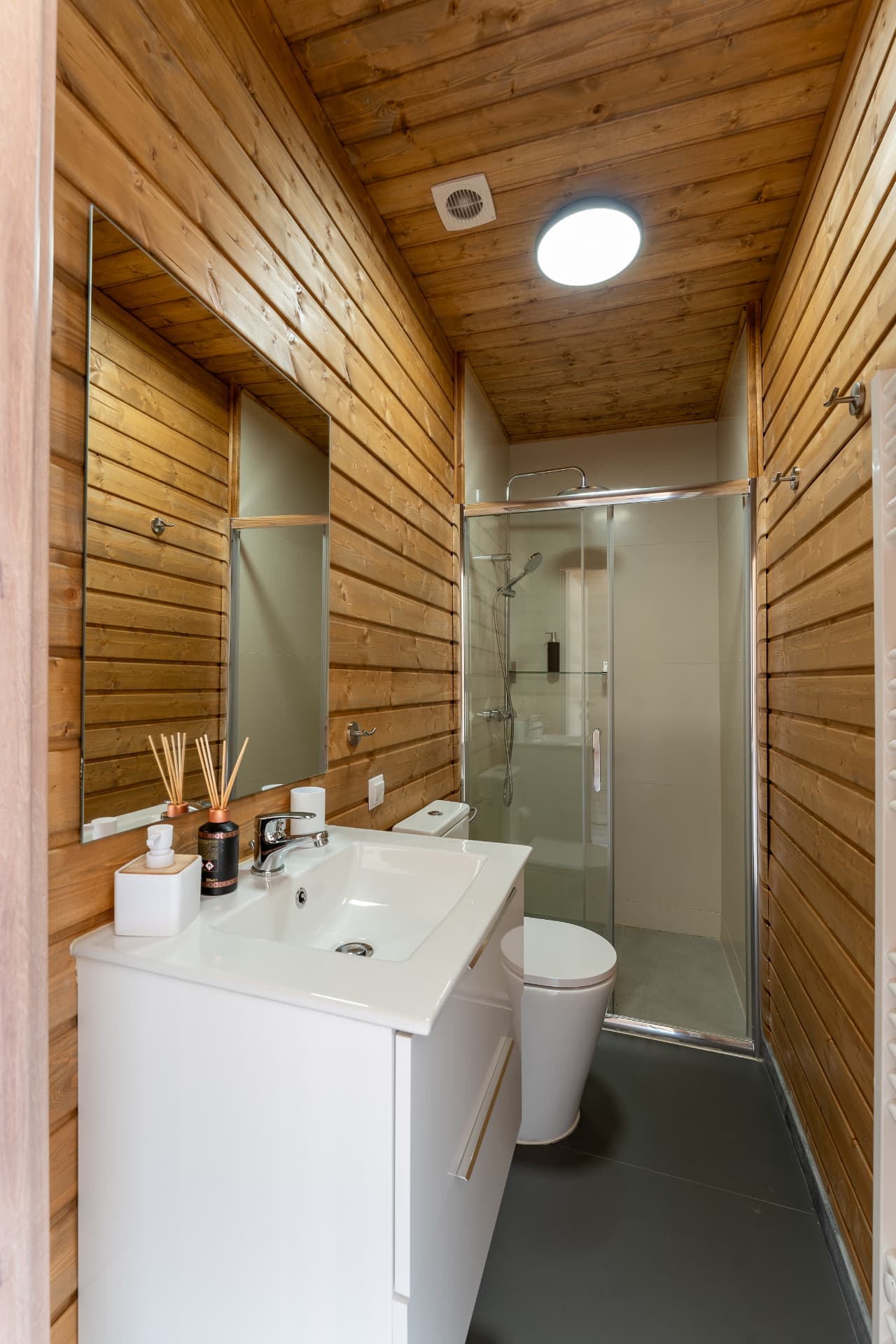 Private bathroom at Cabanele Carmel, with wooden walls, a white sink and a shower cabin