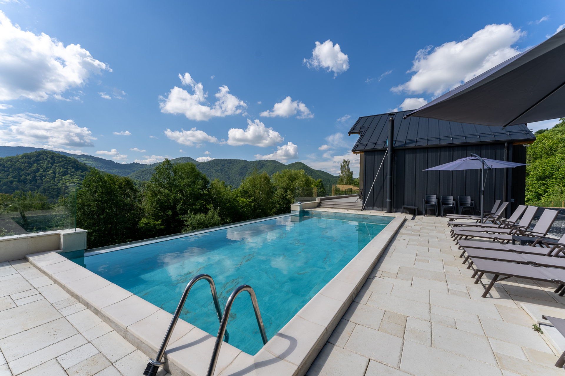 Outdoor pool at Cabanele Carmel, with sun loungers, umbrellas and a view of the mountains
